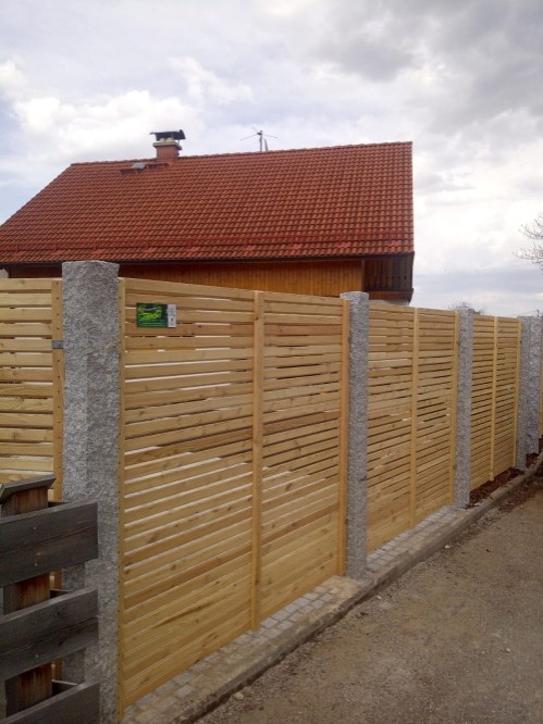 Klassischer Sichtschutzzaun aus Holz mit Natursteinpfosten kombiniert