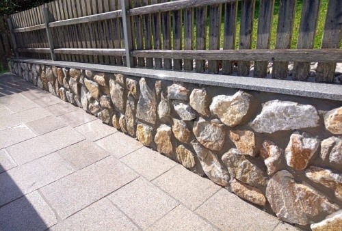 Natursteinmauer mit Holzlattenzaun