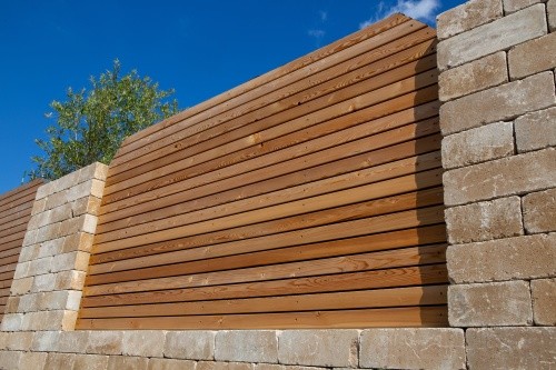 Natursteinmauer mit Holzelementen als Sichtschutz