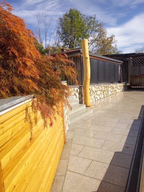 Mauer aus Holz und Naturstein mit Steinterrasse